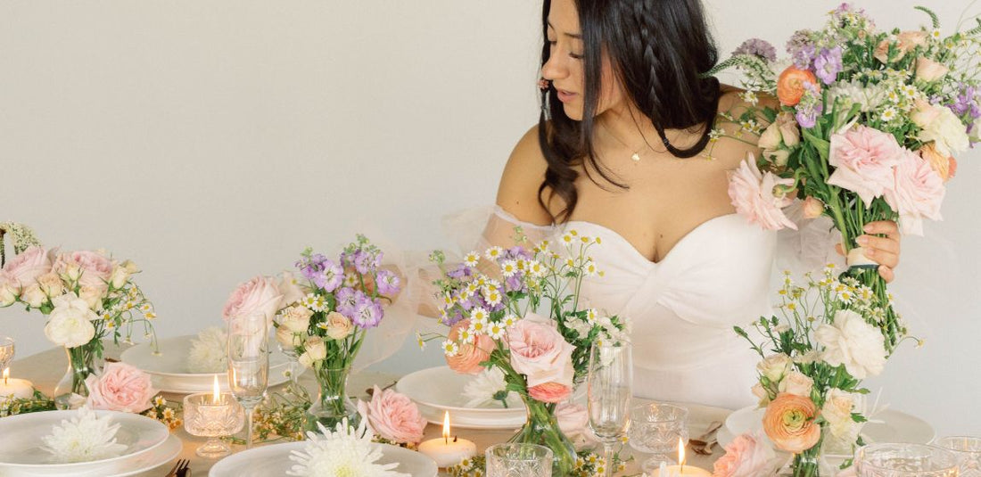 bride holding bouquet and setting up table with ethereal gardens flowers